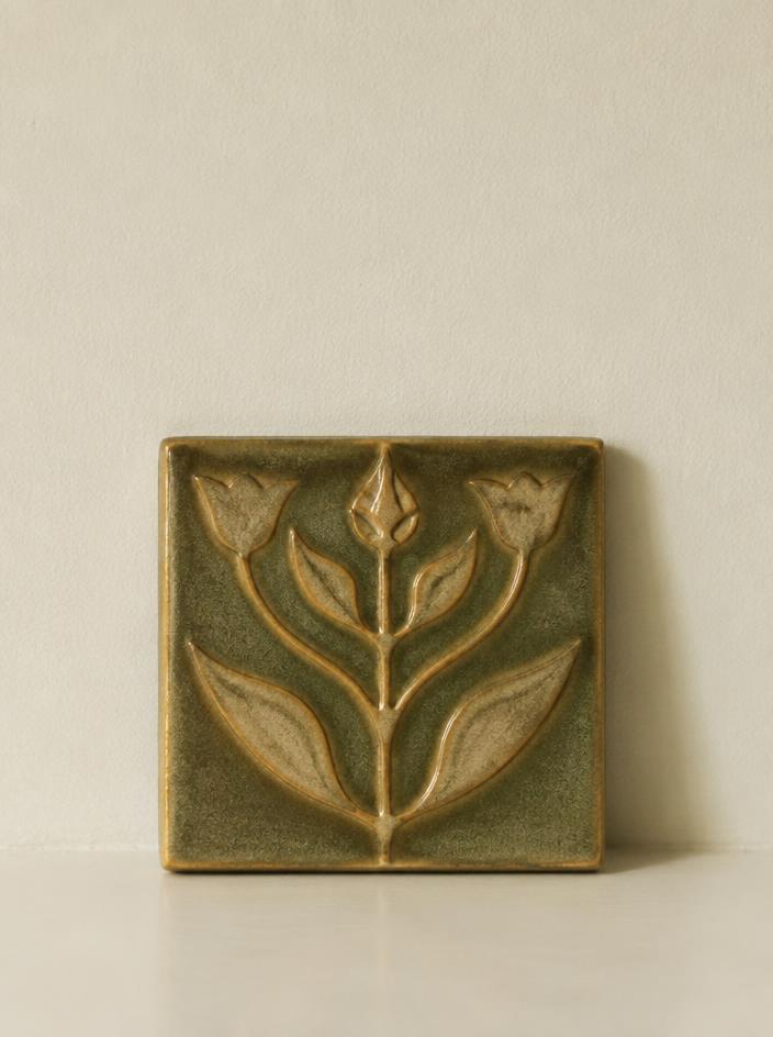 Olive glazed ceramic tile with a stylised plant motif